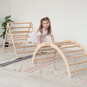little girl climbing foldable eco-friendly wooden pikler triangle and arch